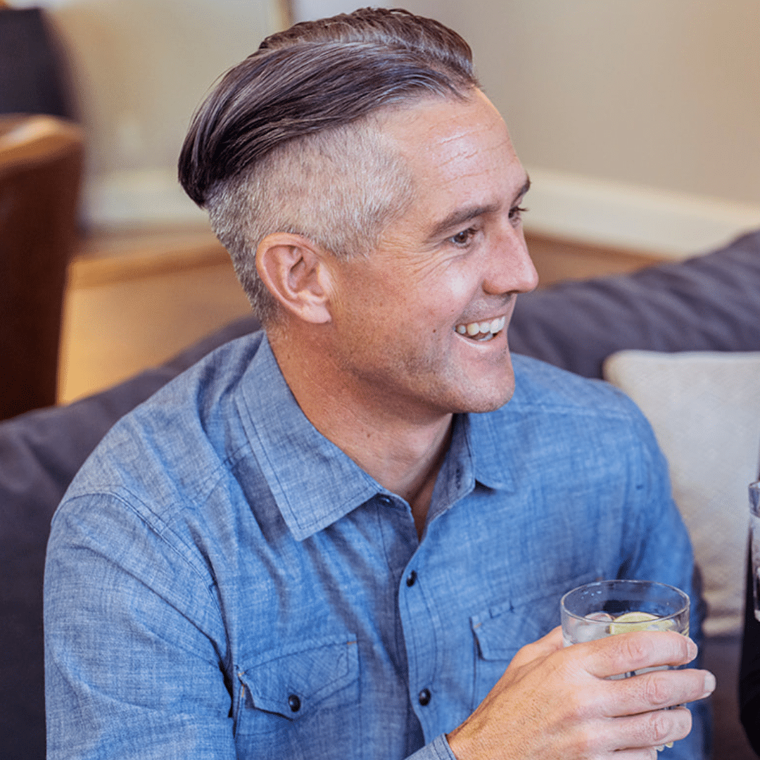 Man smiling drinking a glass of water.